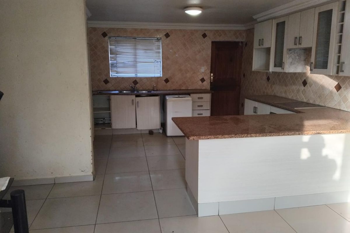 A functional kitchen featuring granite countertops, ample built-in cabinetry, a tiled backsplash, and a breakfast bar, offering a practical layout for daily use.