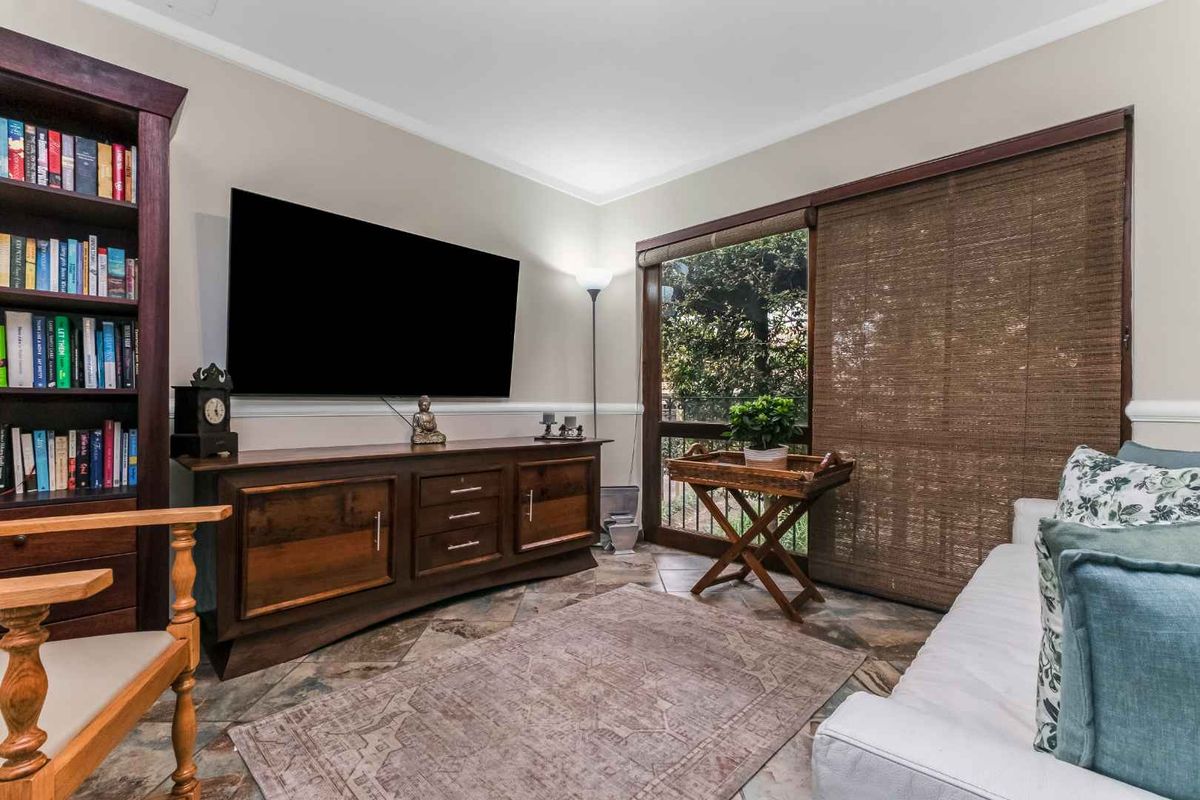 A comfortable living room featuring tiled flooring, chair rail molding, and a sliding glass door providing natural light and garden views.