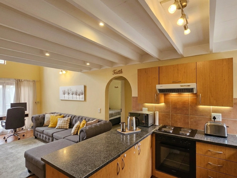 Open-plan living area featuring a kitchen with granite countertops, built-in cabinetry, and exposed ceiling beams, seamlessly flowing into the adjacent living space.