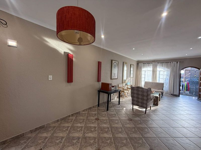 Spacious living area featuring neutral tiled flooring, recessed downlighting, and large arched glass doors providing natural light and access to the exterior.
