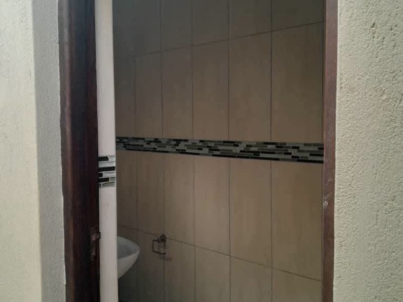 A compact bathroom featuring neutral wall tiles with a decorative mosaic border and tiled flooring.