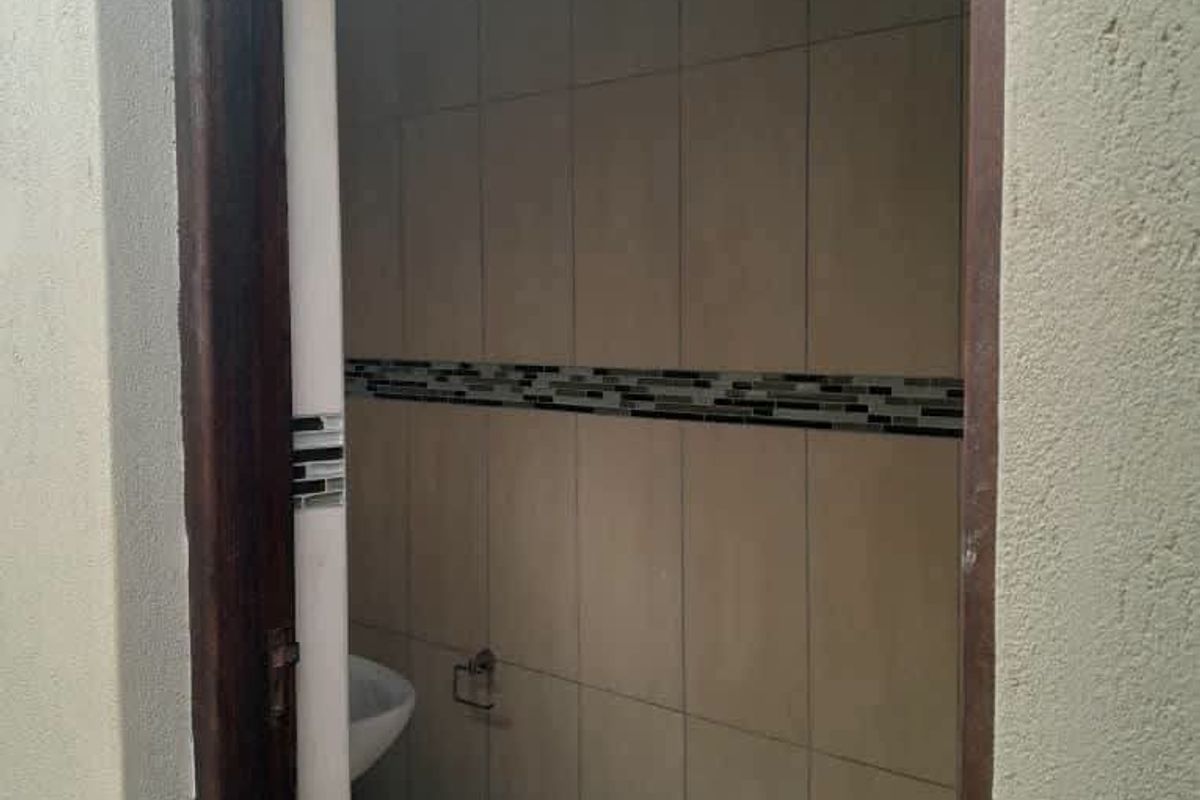 A compact bathroom featuring neutral wall tiles with a decorative mosaic border and tiled flooring.