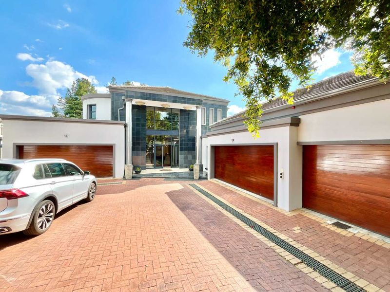 Modern front elevation featuring a triple garage, paved driveway, and a striking stone-clad entrance with large glass doors.