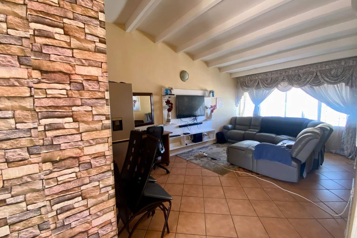 Spacious living area featuring exposed ceiling beams, terracotta floor tiles, and a built-in media unit, offering a comfortable and functional layout.