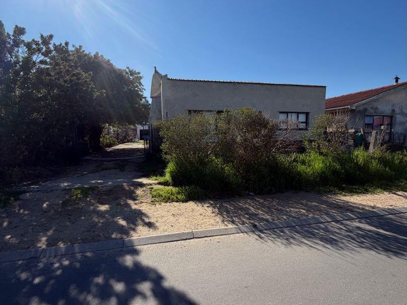 Front view of the property showing the driveway and exterior facade, currently requiring significant landscaping and exterior maintenance.