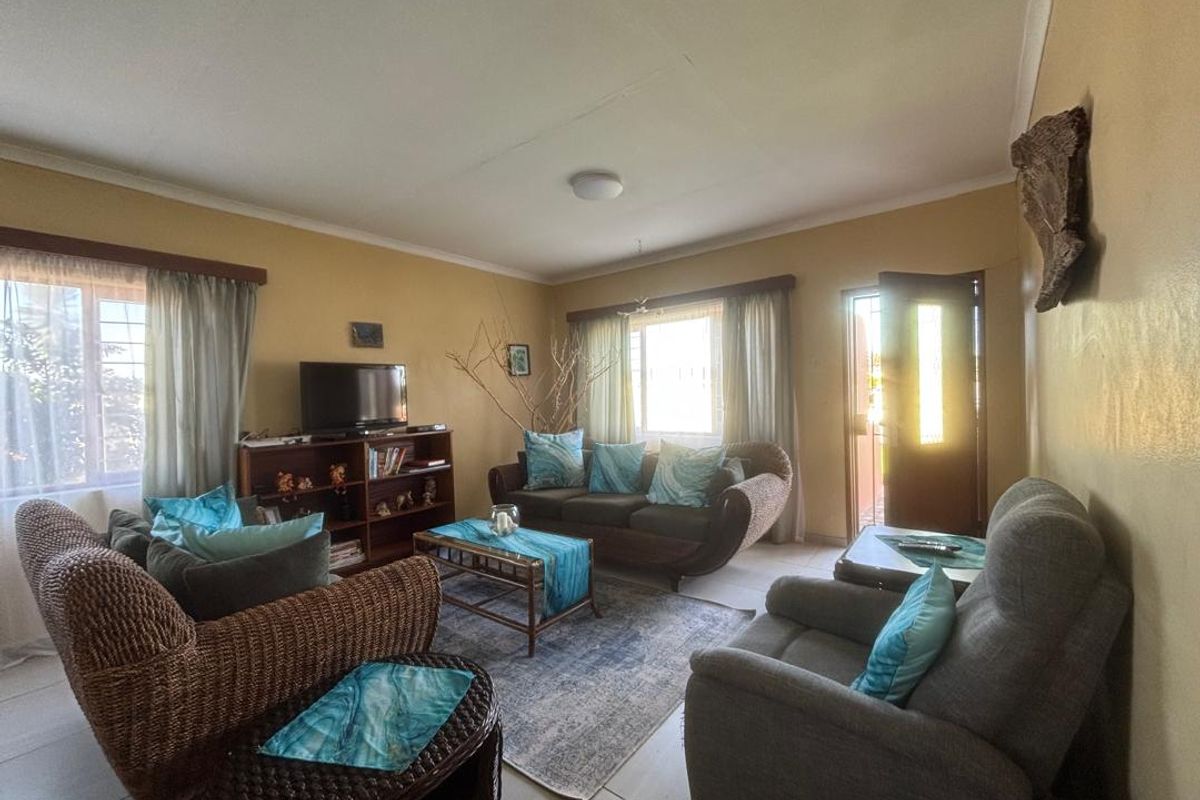 A living room featuring tiled flooring, large windows with curtains, and a direct entrance door, providing a functional and well-lit living space.
