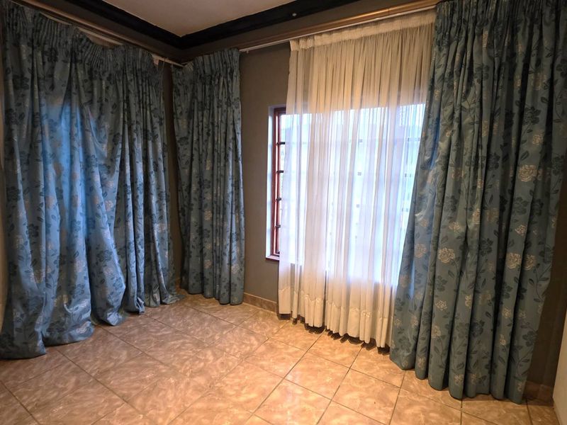 An empty bedroom featuring tiled flooring and built-in cupboards, offering a neutral canvas for personalization.