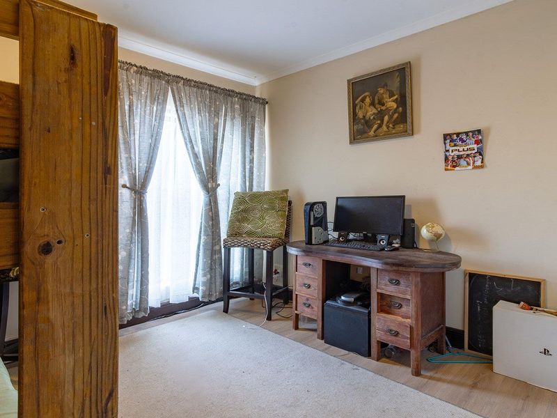 A functional bedroom space featuring laminate flooring and natural light through window treatments, suitable for a variety of bedroom configurations.