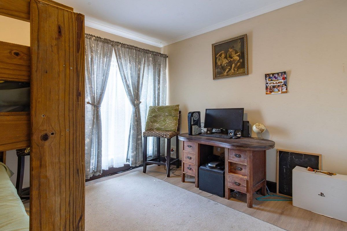 A functional bedroom space featuring laminate flooring and natural light through window treatments, suitable for a variety of bedroom configurations.