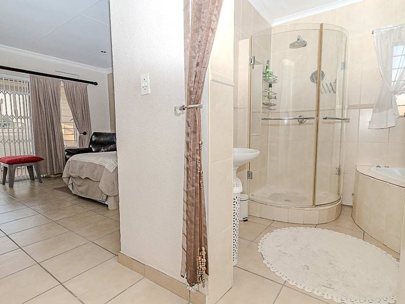 Bathroom featuring a curved glass shower enclosure, built-in bathtub, and pedestal basin, with tiled flooring and direct access to the adjacent living area.