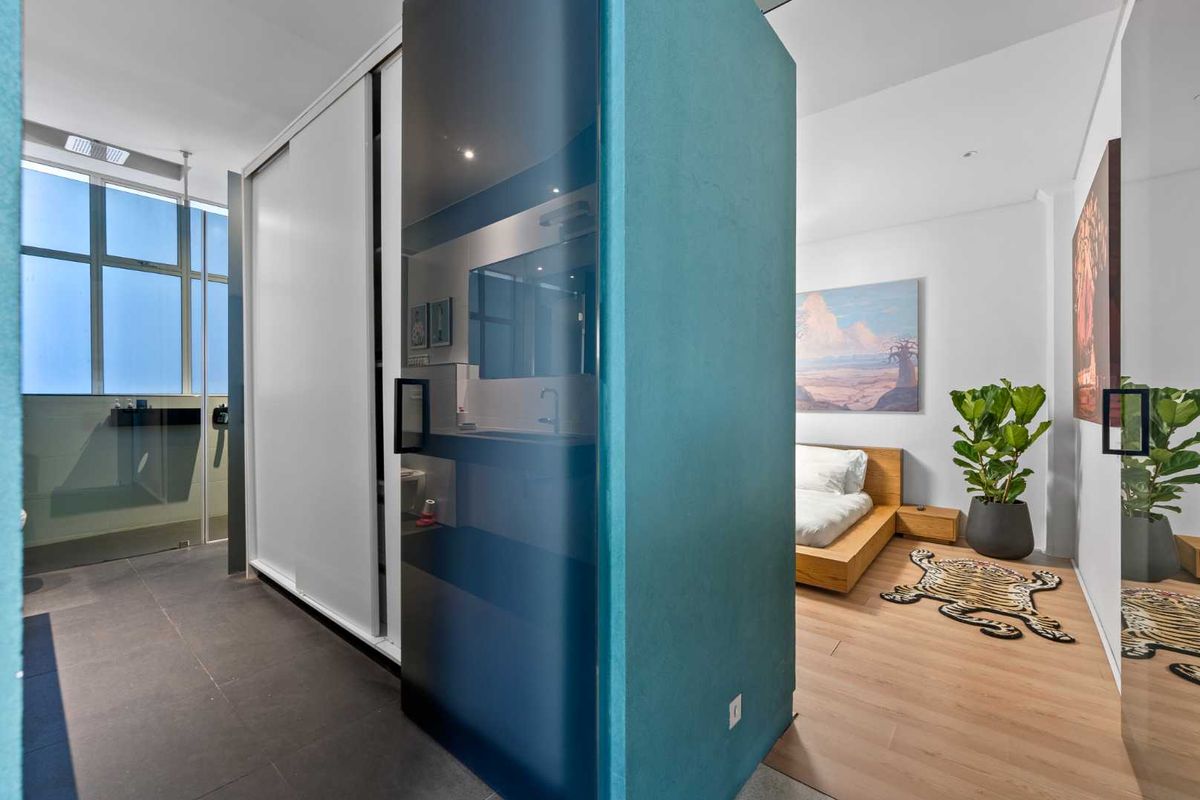 Modern bedroom featuring a central partition wall, sliding wardrobe doors, and a combination of laminate and tiled flooring with recessed lighting.