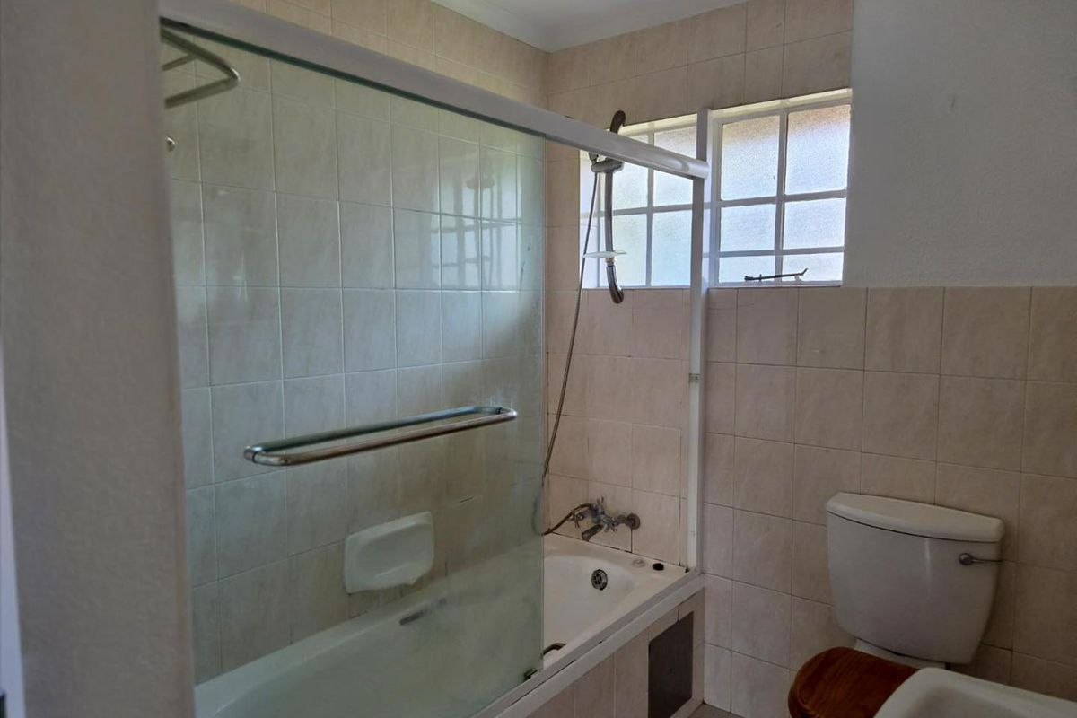 A functional bathroom featuring a combined shower and bathtub unit, tiled walls, and a standard toilet.