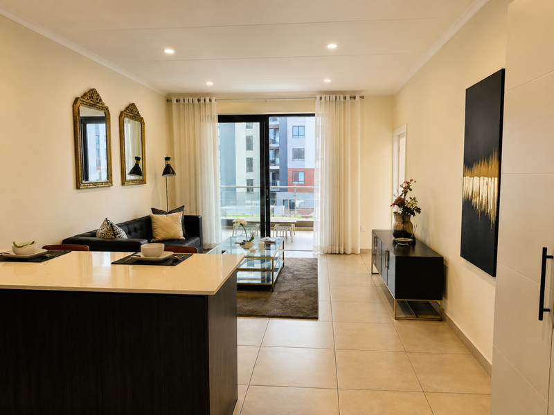 Modern open-plan living area featuring a kitchen island with quartz countertops, tiled flooring, and direct access to a private balcony through sliding glass doors.