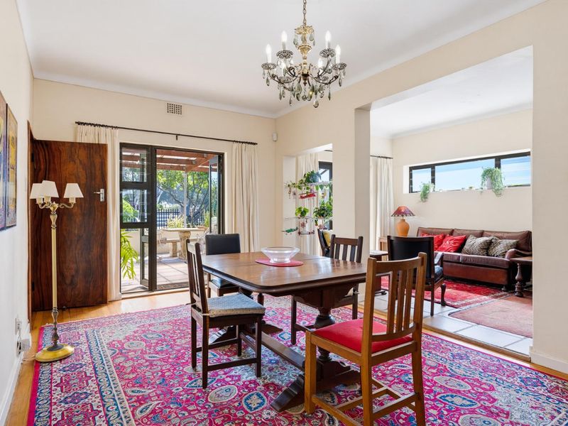 Open plan dining and living area featuring hardwood flooring, a classic chandelier, and direct access to an outdoor patio through sliding glass doors.