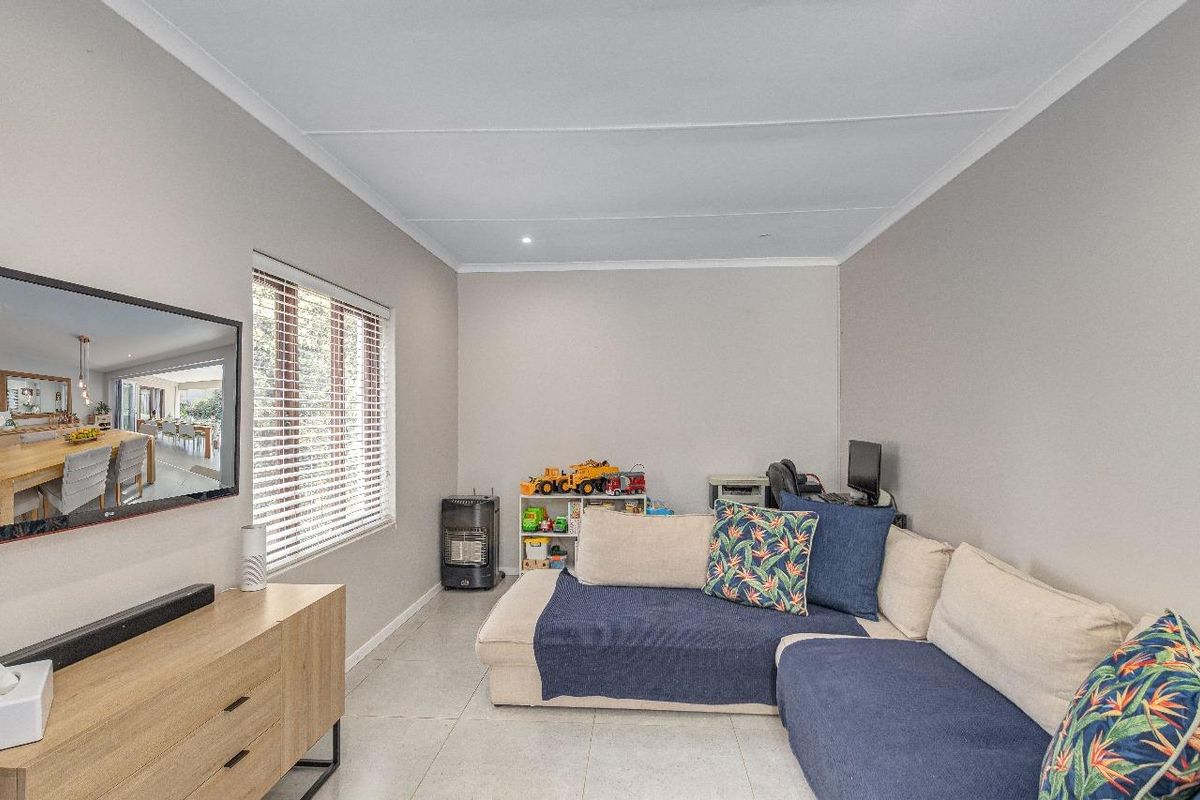 A well-maintained living room featuring neutral tiled flooring, coved ceilings, and venetian blinds, providing a comfortable and functional space.