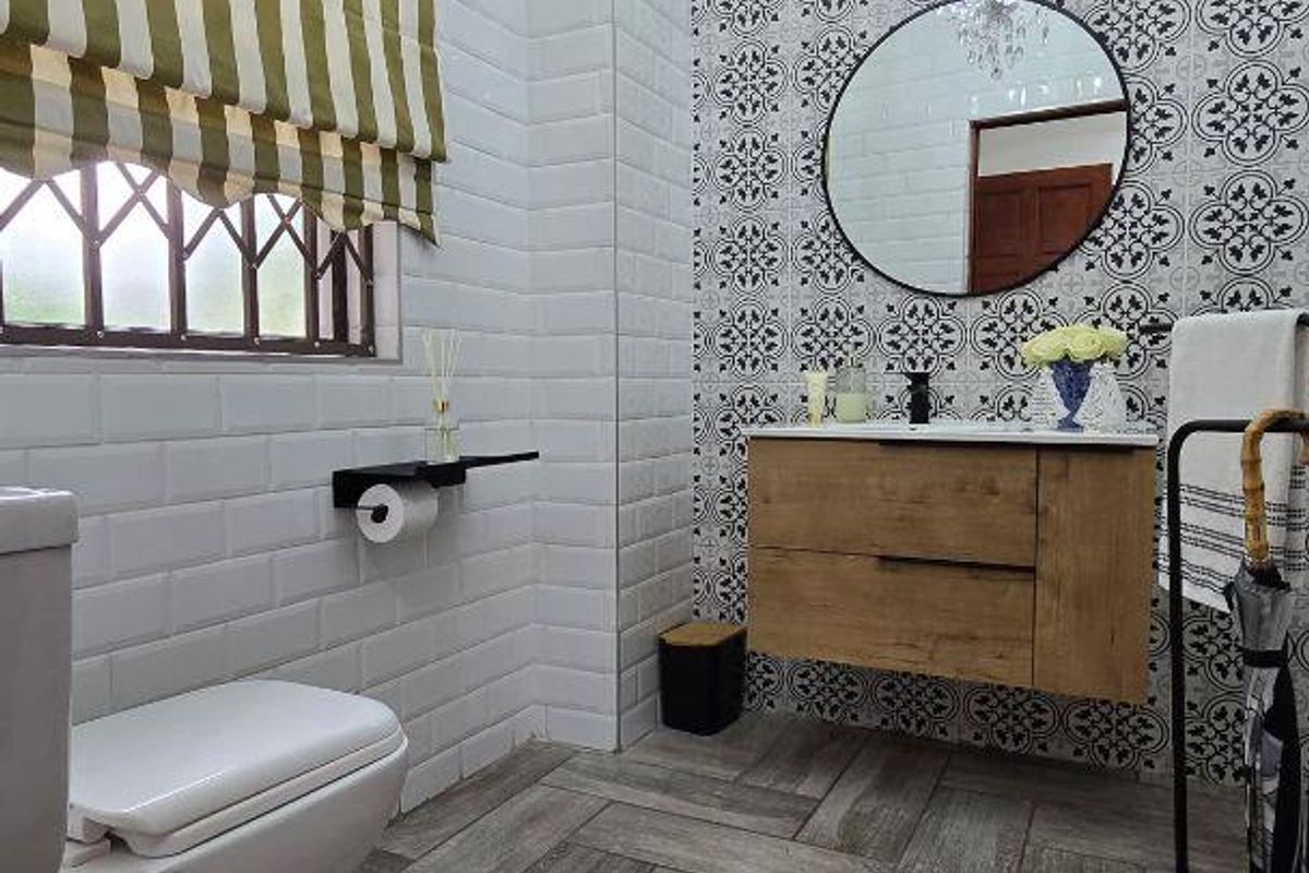 Modern bathroom featuring a wall-mounted vanity, striking patterned feature wall, herringbone floor tiling, and elegant crystal chandelier lighting.