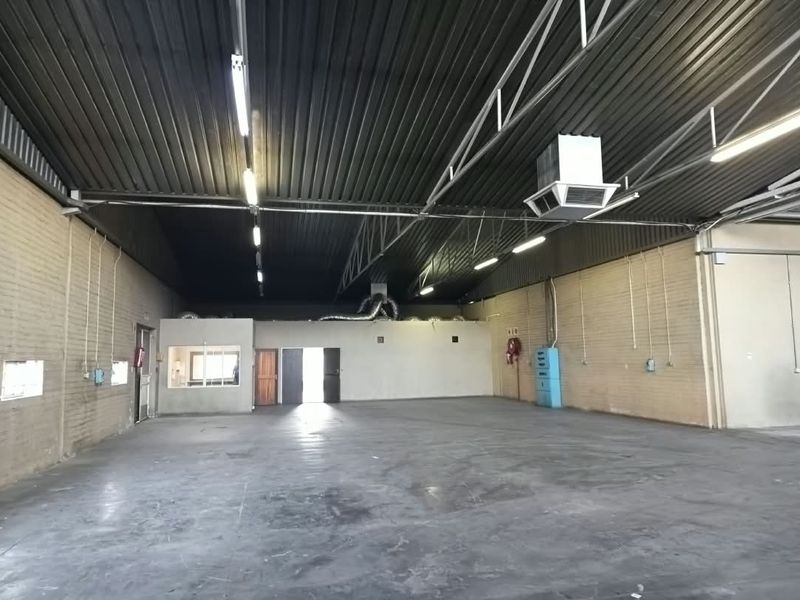 Spacious open-plan office or industrial workspace featuring high exposed ceilings, concrete flooring, and integrated HVAC systems, suitable for various commercial business operations.