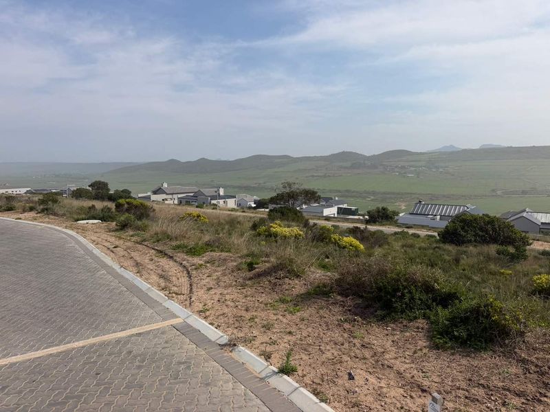 A view from the vacant residential plot overlooking the surrounding landscape and neighboring estate homes.