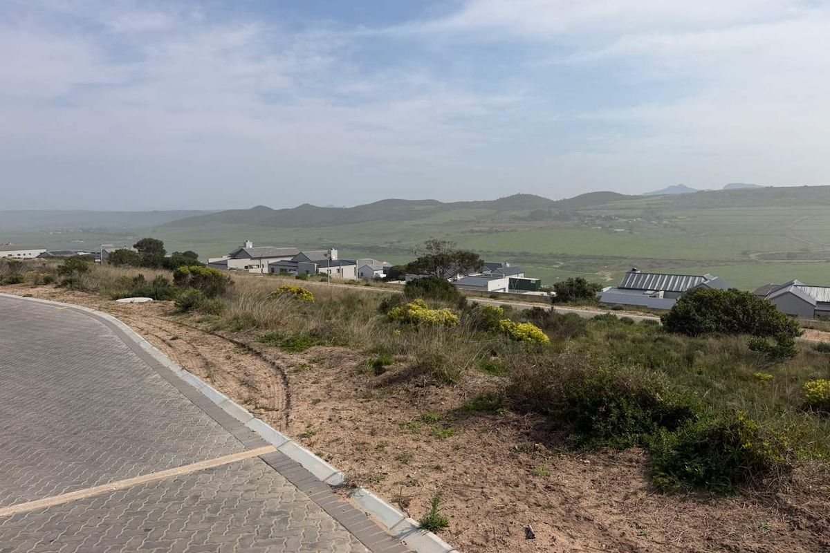 A view from the vacant residential plot overlooking the surrounding landscape and neighboring estate homes.