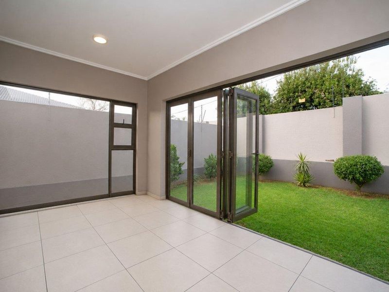 A bright, modern covered patio featuring large aluminium stacker doors that open onto a private, well-maintained garden area.