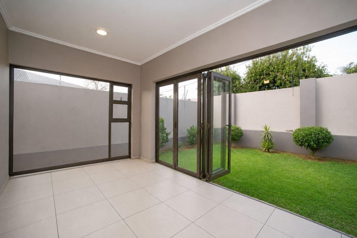 A bright, modern covered patio featuring large aluminium stacker doors that open onto a private, well-maintained garden area.