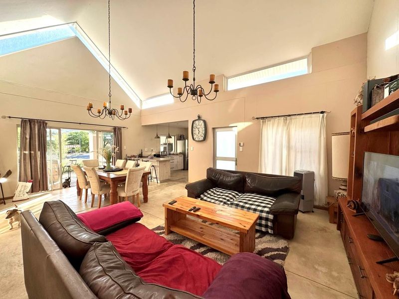 Spacious open-plan living and dining area featuring a high vaulted ceiling, clerestory windows for natural light, and seamless flow to the kitchen.