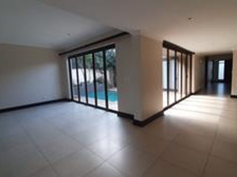Spacious open-plan living area featuring large stacking glass doors that provide seamless access to the outdoor pool area and natural light.