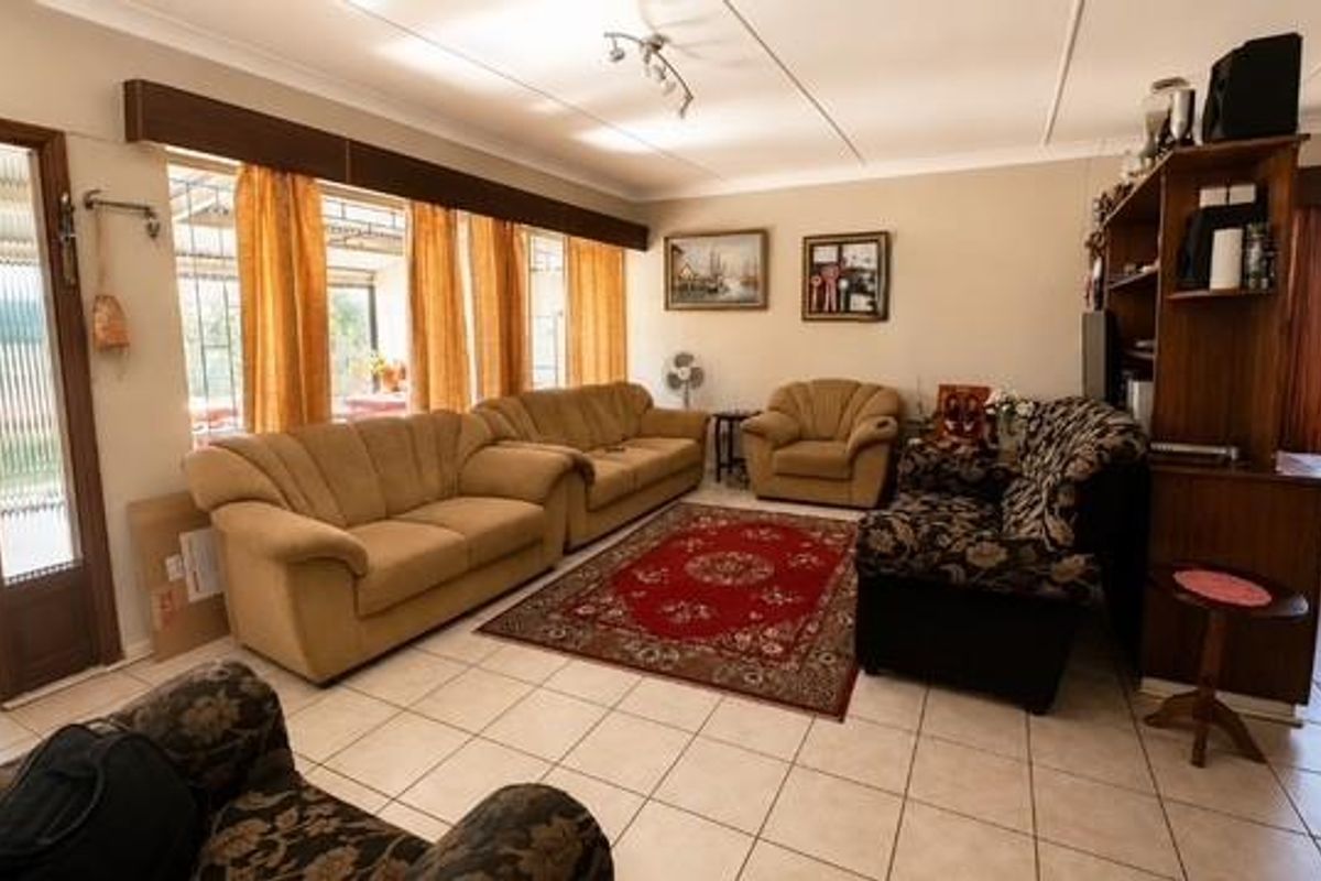 Spacious living room featuring ceramic floor tiles, large windows with natural light, and direct access to an enclosed patio area.