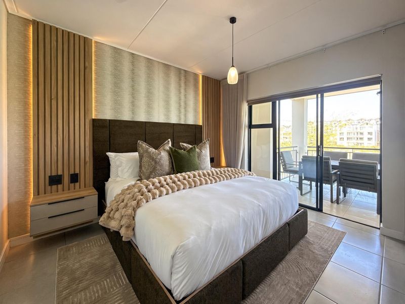 Modern bedroom featuring timber slat wall paneling with integrated LED lighting, tiled floors, and direct access to a private balcony through sliding glass doors.