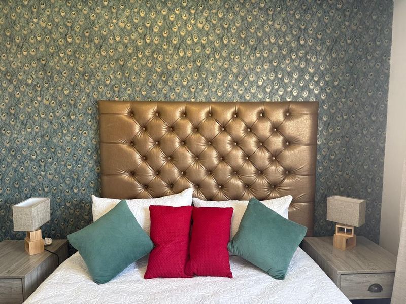 A well-maintained bedroom featuring a decorative peacock-patterned feature wall and a tufted headboard.