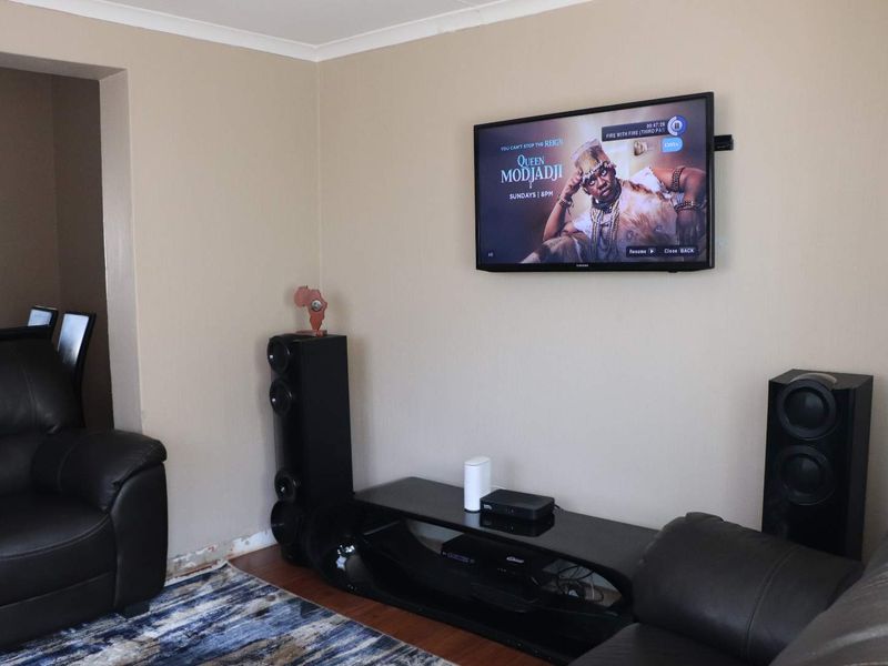 A living room area featuring laminate flooring and coved ceilings, currently showing missing skirting boards along the base of the wall.