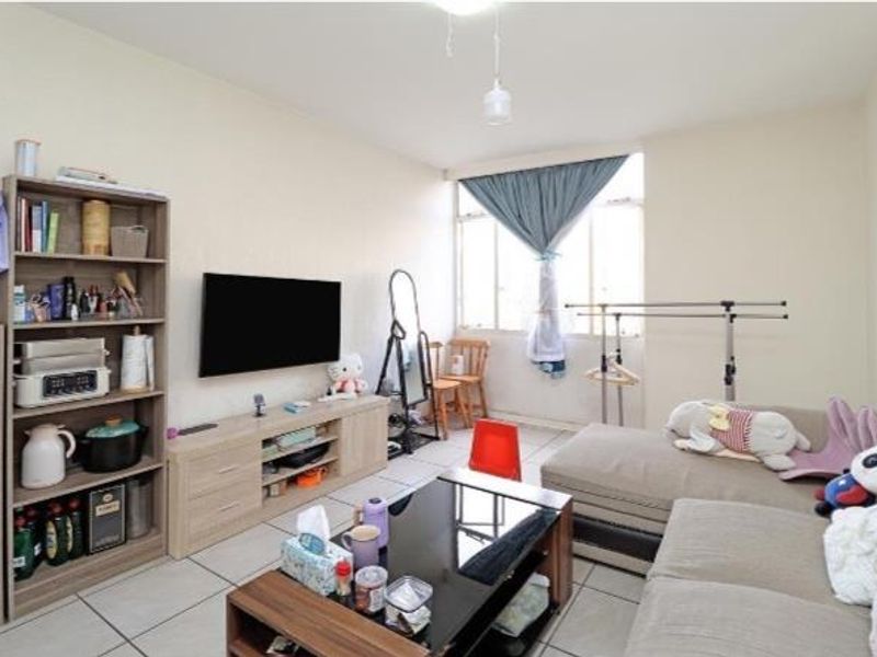 A functional living room featuring tiled flooring and a large window, providing a neutral base for potential interior updates.