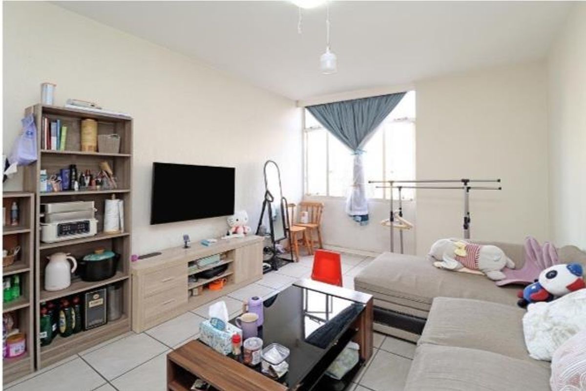 A functional living room featuring tiled flooring and a large window, providing a neutral base for potential interior updates.