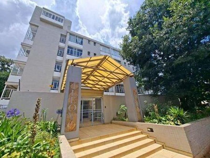 Front entrance of the apartment building featuring a covered walkway, tiled steps, and secure gated access.