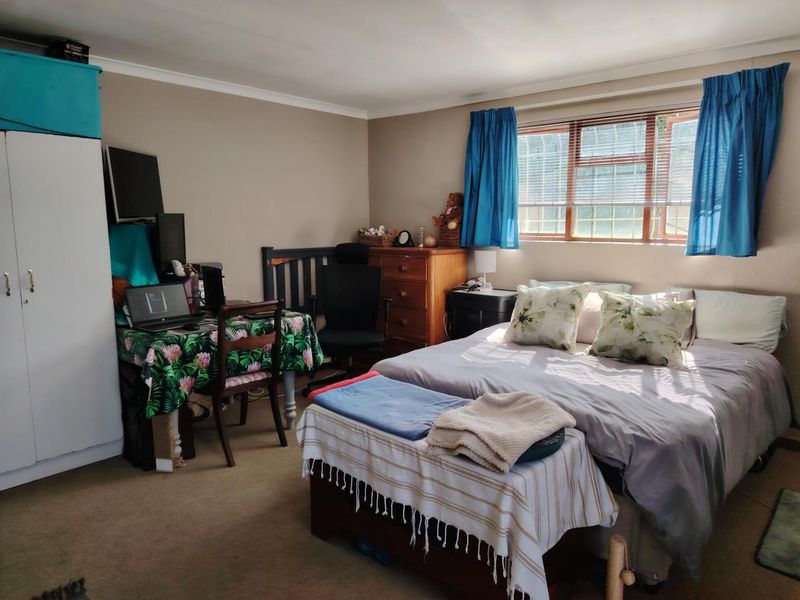 A functional bedroom featuring a built-in wardrobe and a window fitted with security bars, providing natural light and standard storage space.