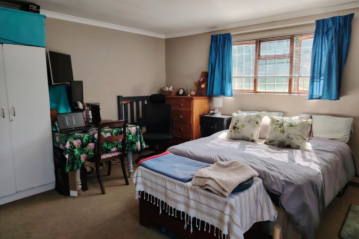 A functional bedroom featuring a built-in wardrobe and a window fitted with security bars, providing natural light and standard storage space.