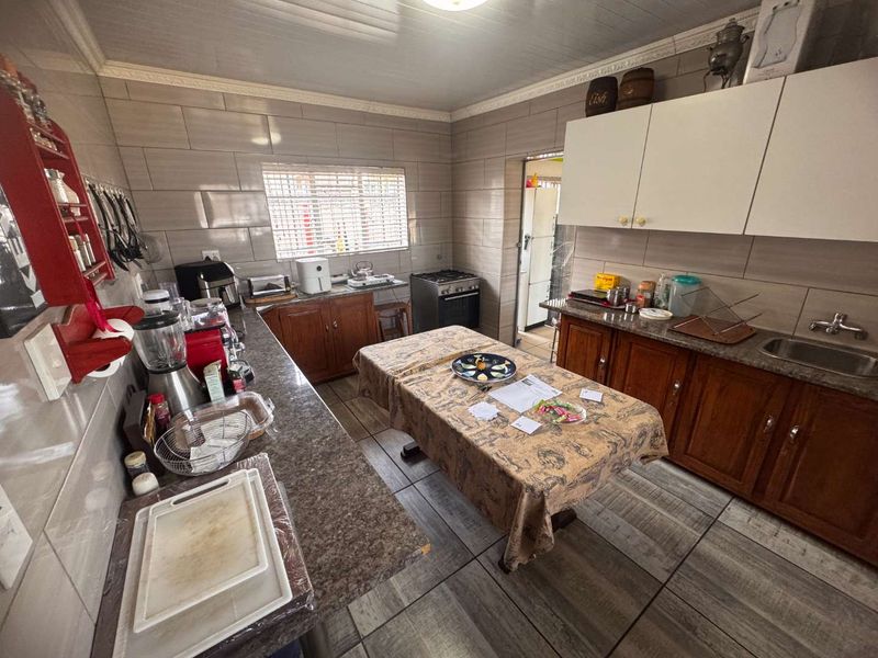 A functional kitchen featuring tiled walls, wood-finish cabinetry, laminate countertops, and a freestanding stove, offering a practical layout for daily meal preparation.
