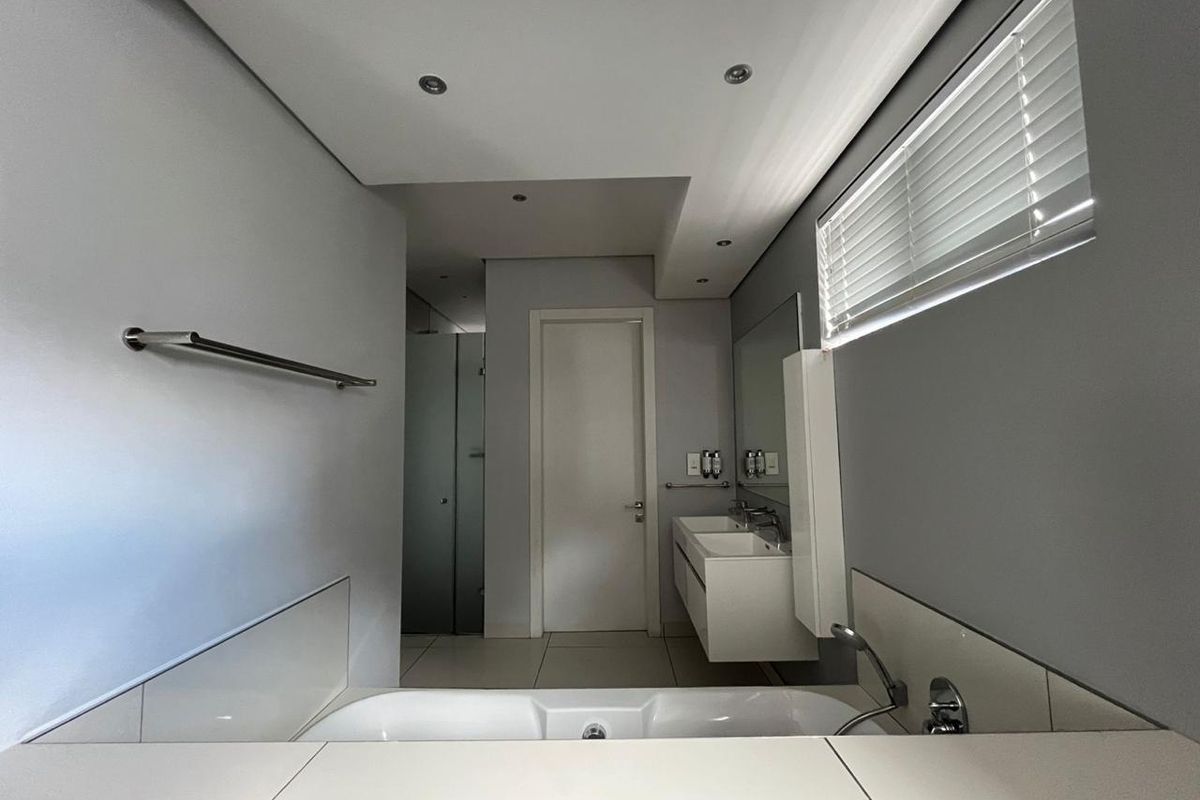 Modern bathroom featuring a built-in bathtub, double wall-mounted vanity, tiled flooring, and recessed lighting with clean, neutral finishes.