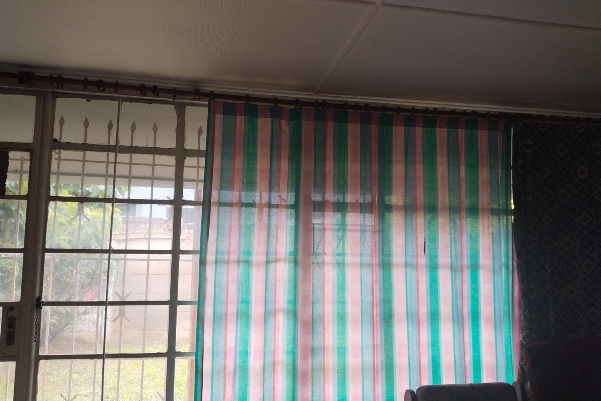 A living area featuring large windows with integrated security bars and a tiled ceiling finish.