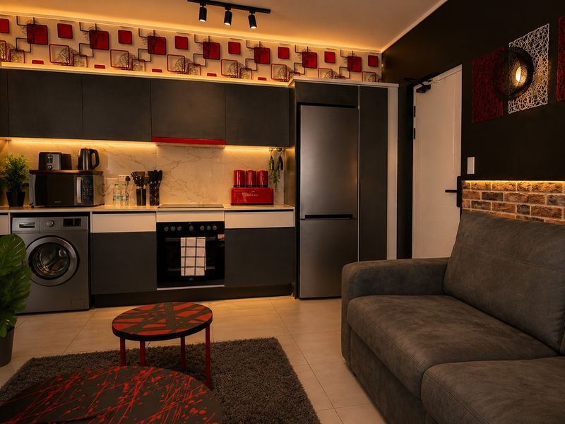 Modern open-plan living area featuring a sleek kitchen with built-in appliances, contemporary cabinetry, ambient LED lighting, and a stylish exposed brick accent wall.