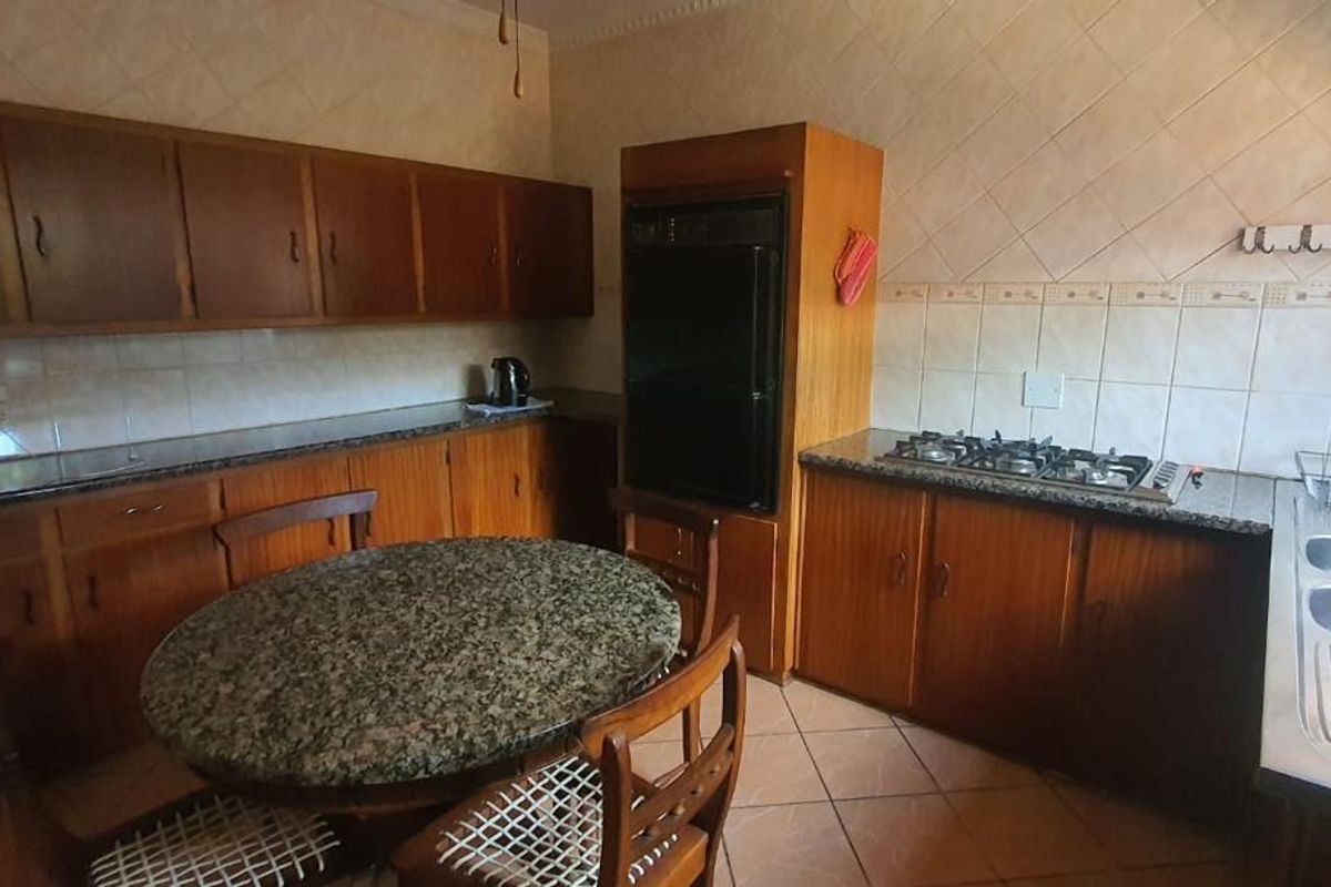 A functional kitchen featuring wooden cabinetry, granite countertops, a built-in oven, gas hob, and a double stainless steel sink.