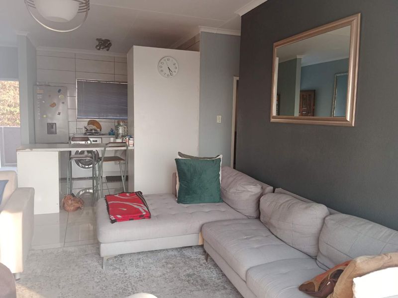 Open plan living area featuring a combined kitchen with breakfast counter and tiled flooring, seamlessly flowing into the lounge space.