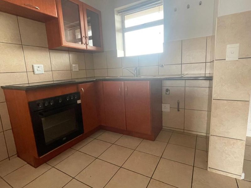 A functional kitchen featuring built-in wooden cabinetry, a built-in oven, tiled backsplash, and tiled flooring with dedicated plumbing for appliances.