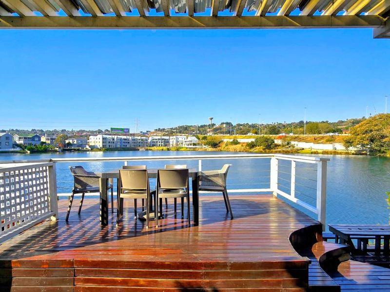 An elevated timber deck patio featuring a pergola and direct water views, providing an ideal outdoor entertainment space.