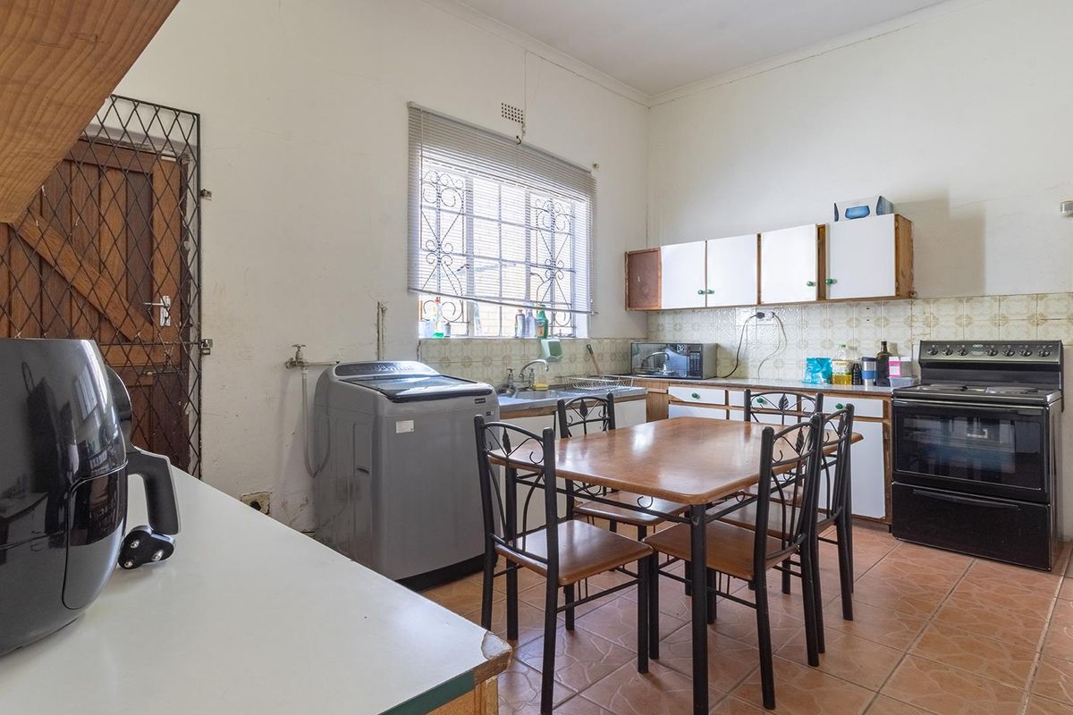 A functional kitchen featuring tiled flooring, built-in cabinetry, a stainless steel sink, and a freestanding oven, offering potential for modernization and renovation.