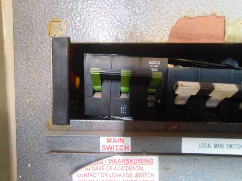 Close-up view of an industrial electrical distribution board featuring a 100A main circuit breaker switch.