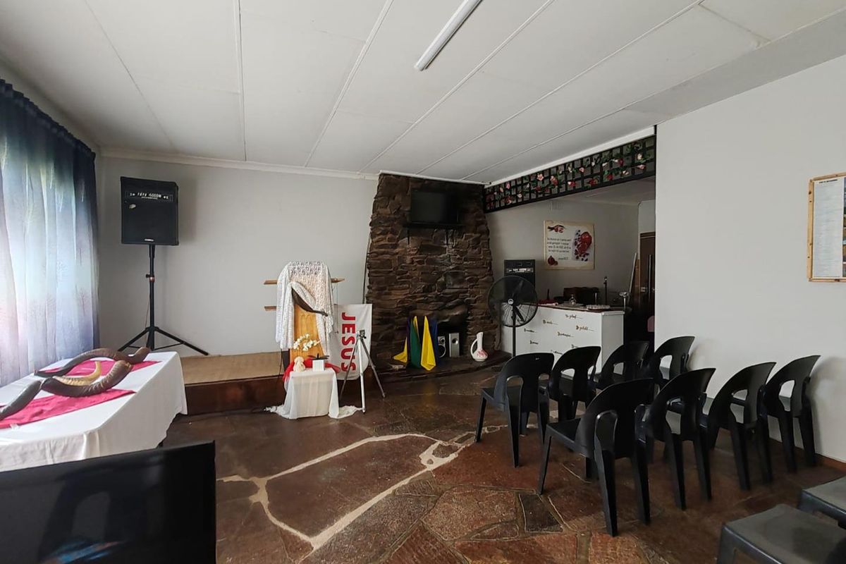 A multi-purpose living space featuring a natural stone fireplace, flagstone flooring, and a raised platform area suitable for various uses.
