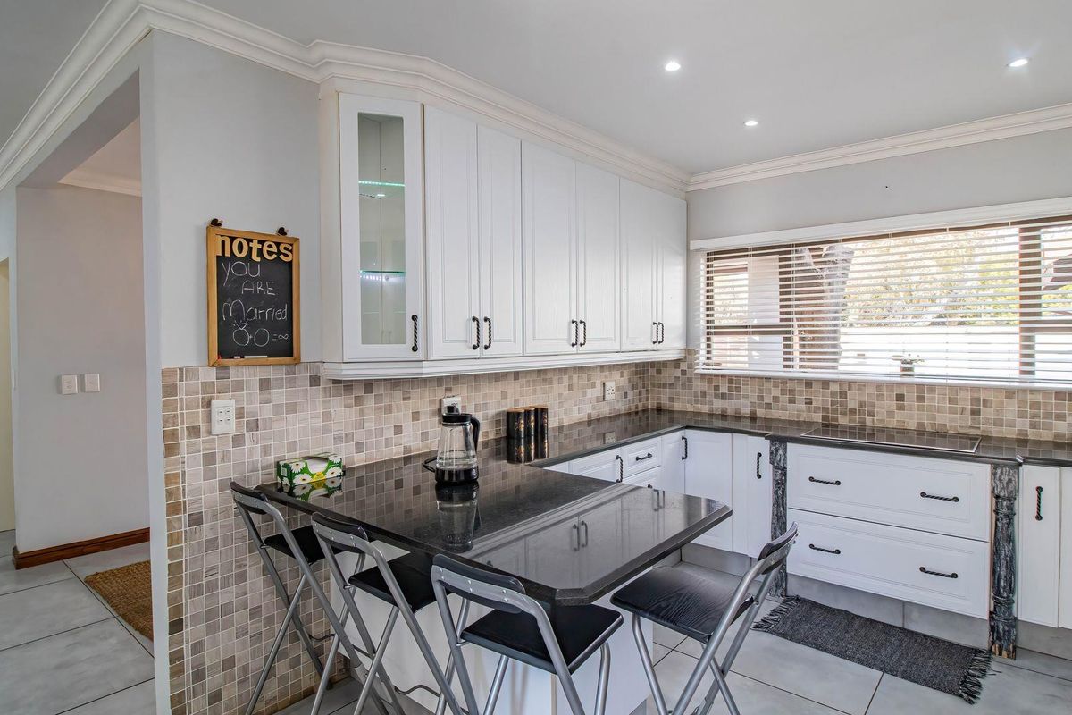 A well-maintained kitchen featuring white cabinetry, black granite countertops, mosaic tile backsplash, and modern recessed lighting.
