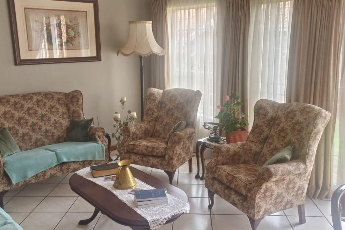 A comfortable living room featuring tiled flooring and large sliding glass doors that provide direct access to the rear garden area.