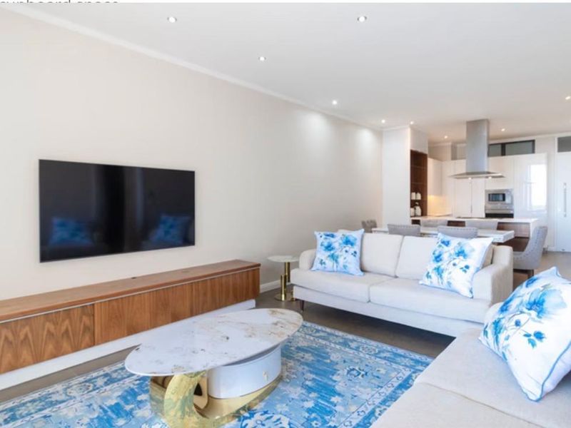 Modern open-plan living area featuring a sleek kitchen with built-in appliances, recessed lighting, and a seamless flow between the kitchen and lounge space.